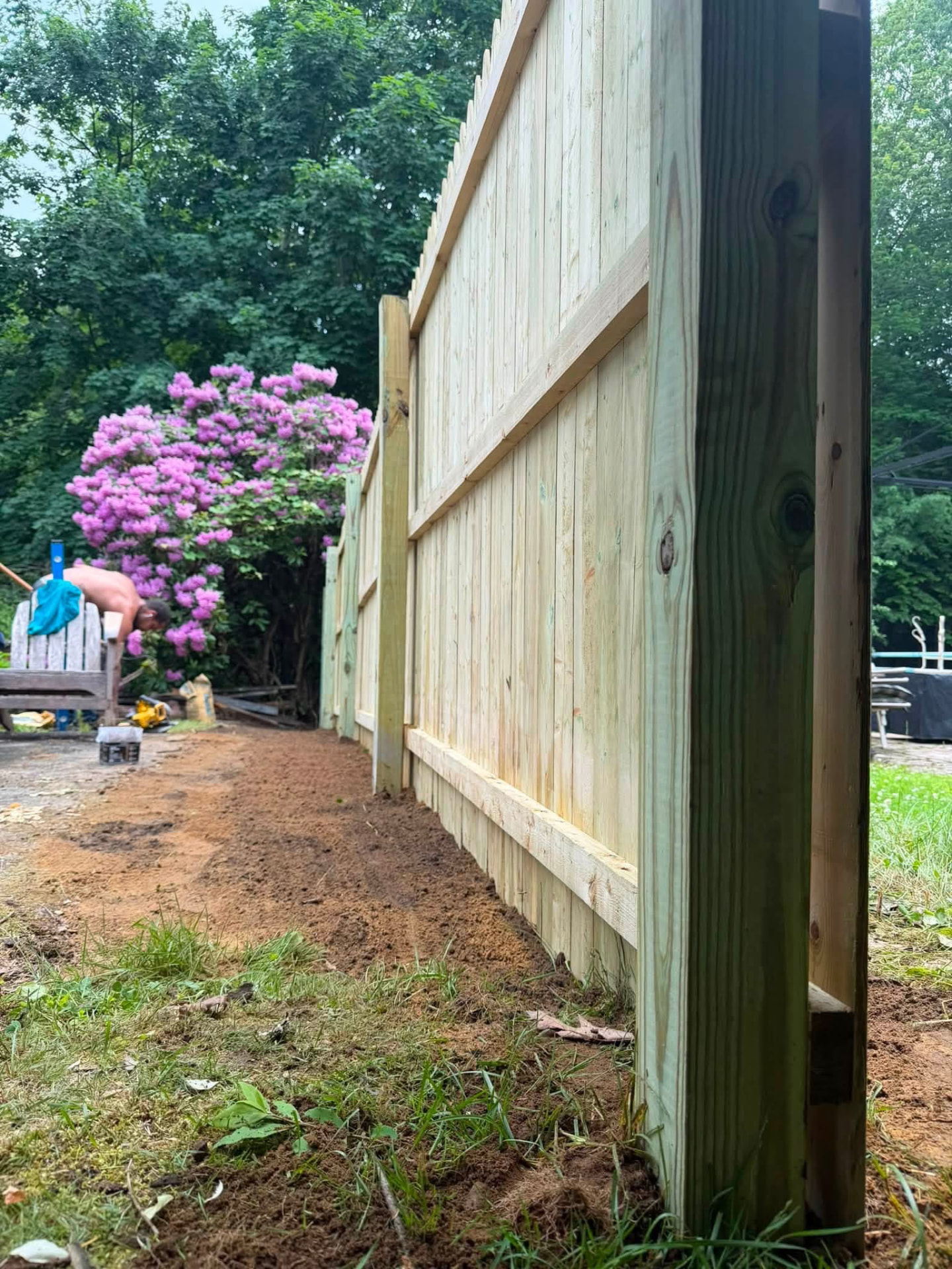 Pressure-treated wood privacy fence with posts and rails during installation