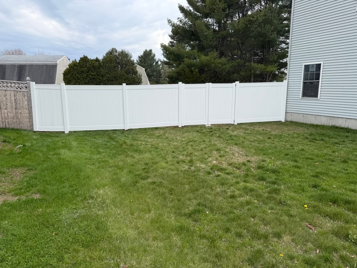 New white vinyl privacy fence installed along a backyard in Southern Maine