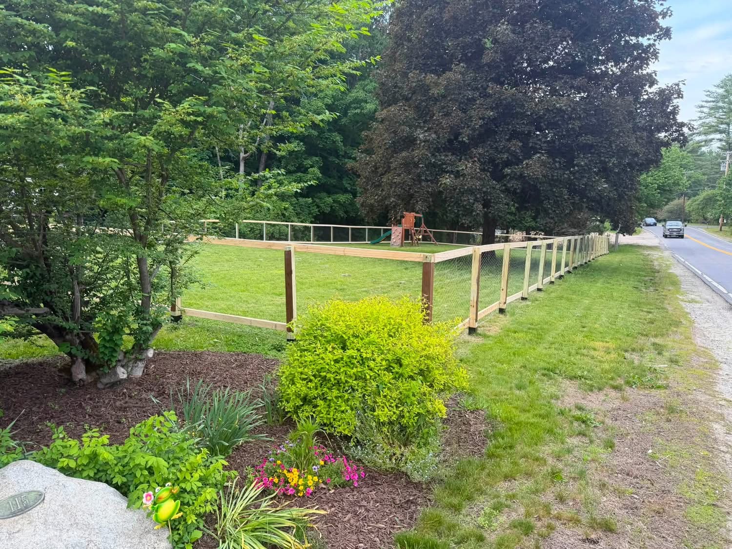 Wood frame and wire yard fence installed along a front lawn